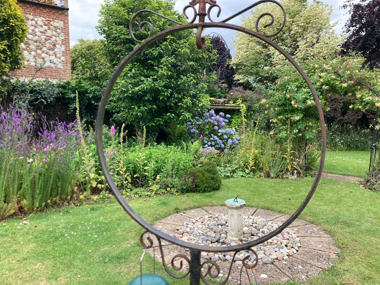 A circular wrought-iron garden feature with lavender borders beyond