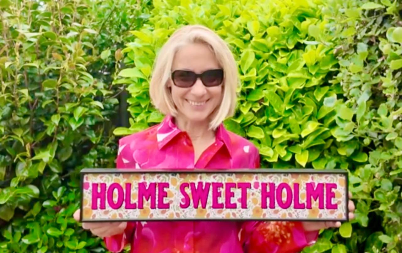 A visitor holding a sign reading 'Holme Sweet Holme'