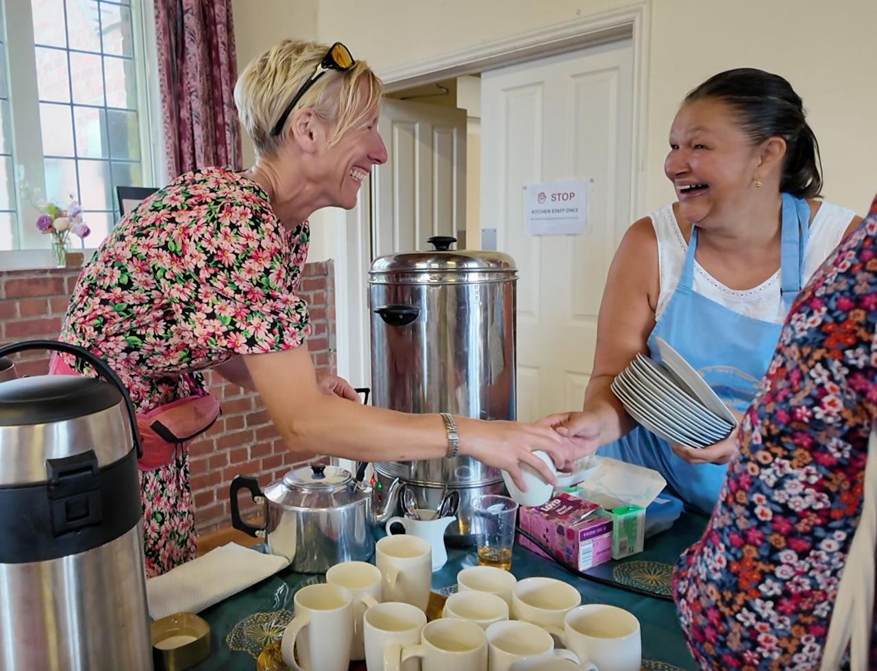 Volunteers sharing a laugh beside the tea urn