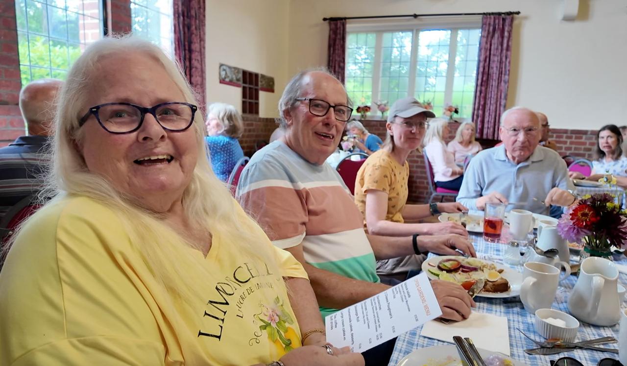 Visitors enjoying tea and cake at a table in the Village Hall