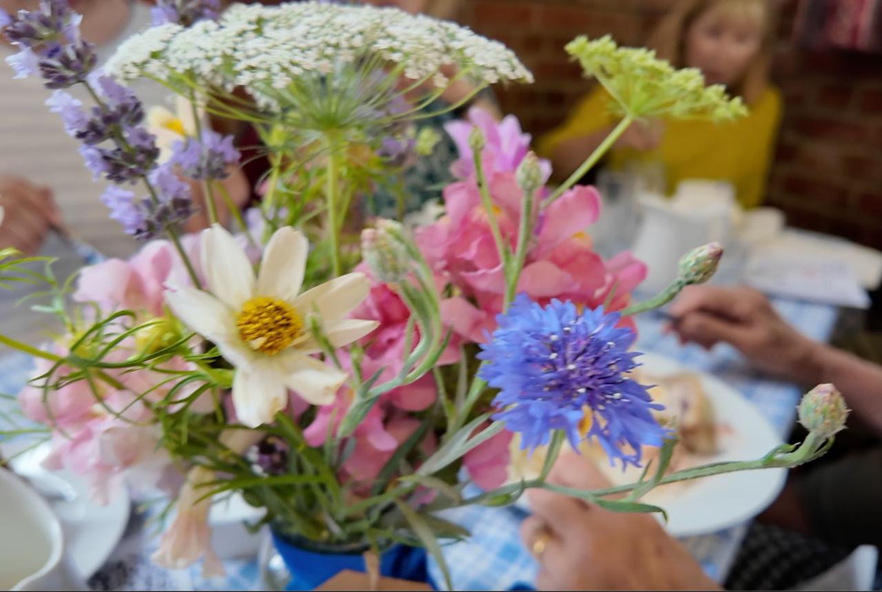 A posy of cornflowers, cosmos and garden flowers on a tea table