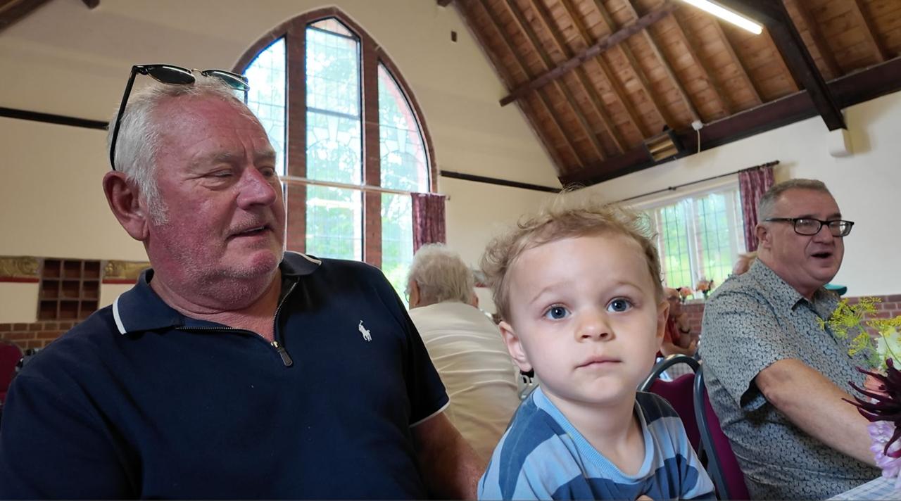 A grandfather and toddler at the tables in the Village Hall