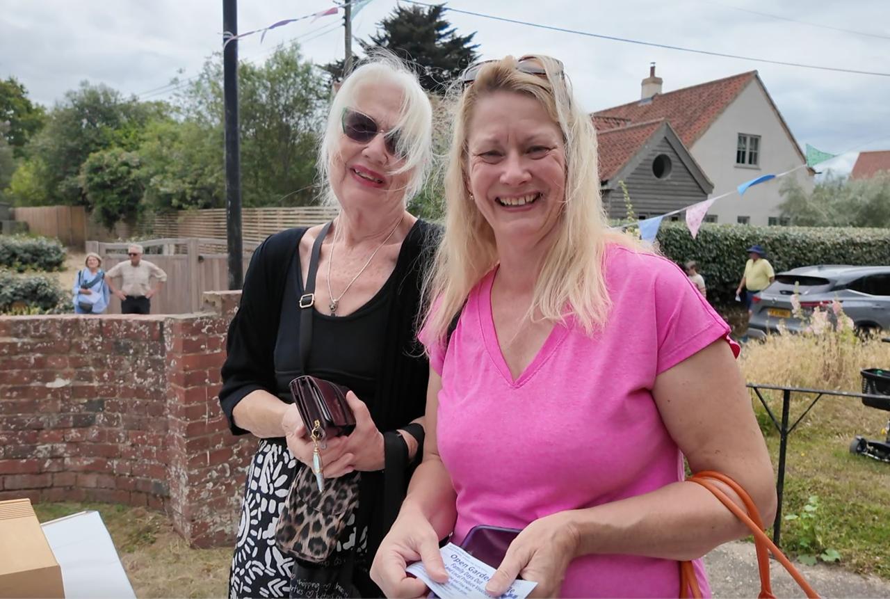 Two smiling visitors in front of a flint wall
