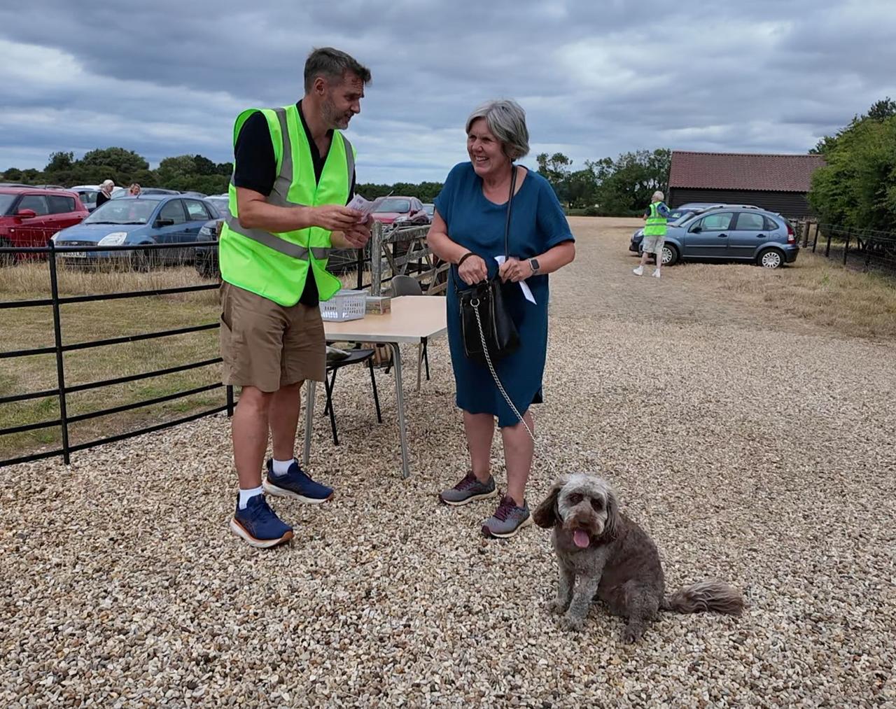 A volunteer chatting with a visitor and her dog at the car park