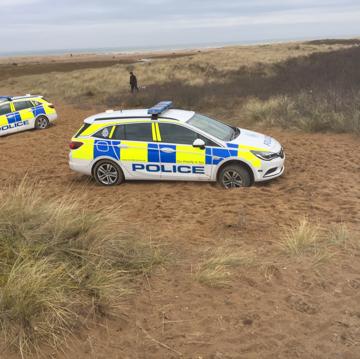 Police vehicles stuck on the beach