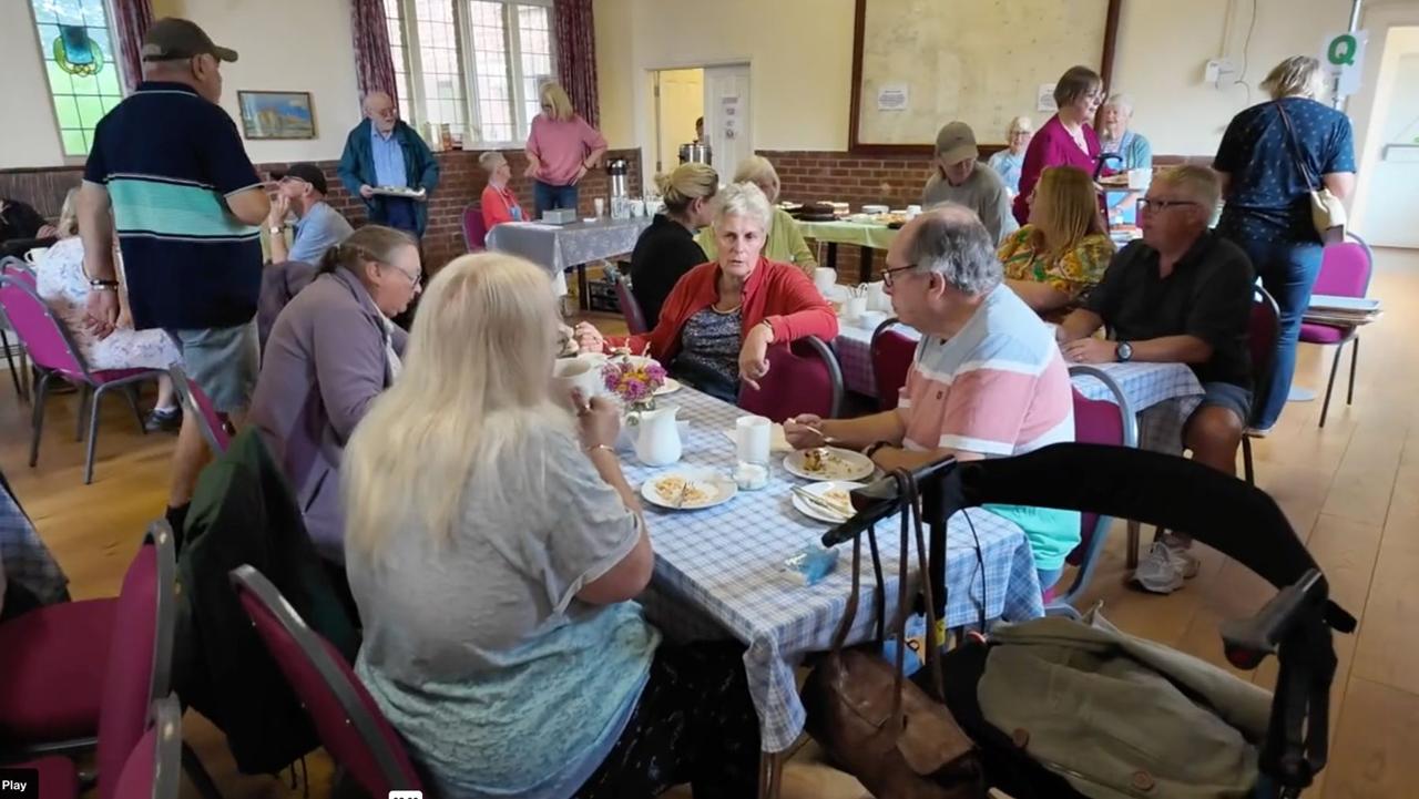 Visitors enjoying tea and cake at tables in the Village Hall