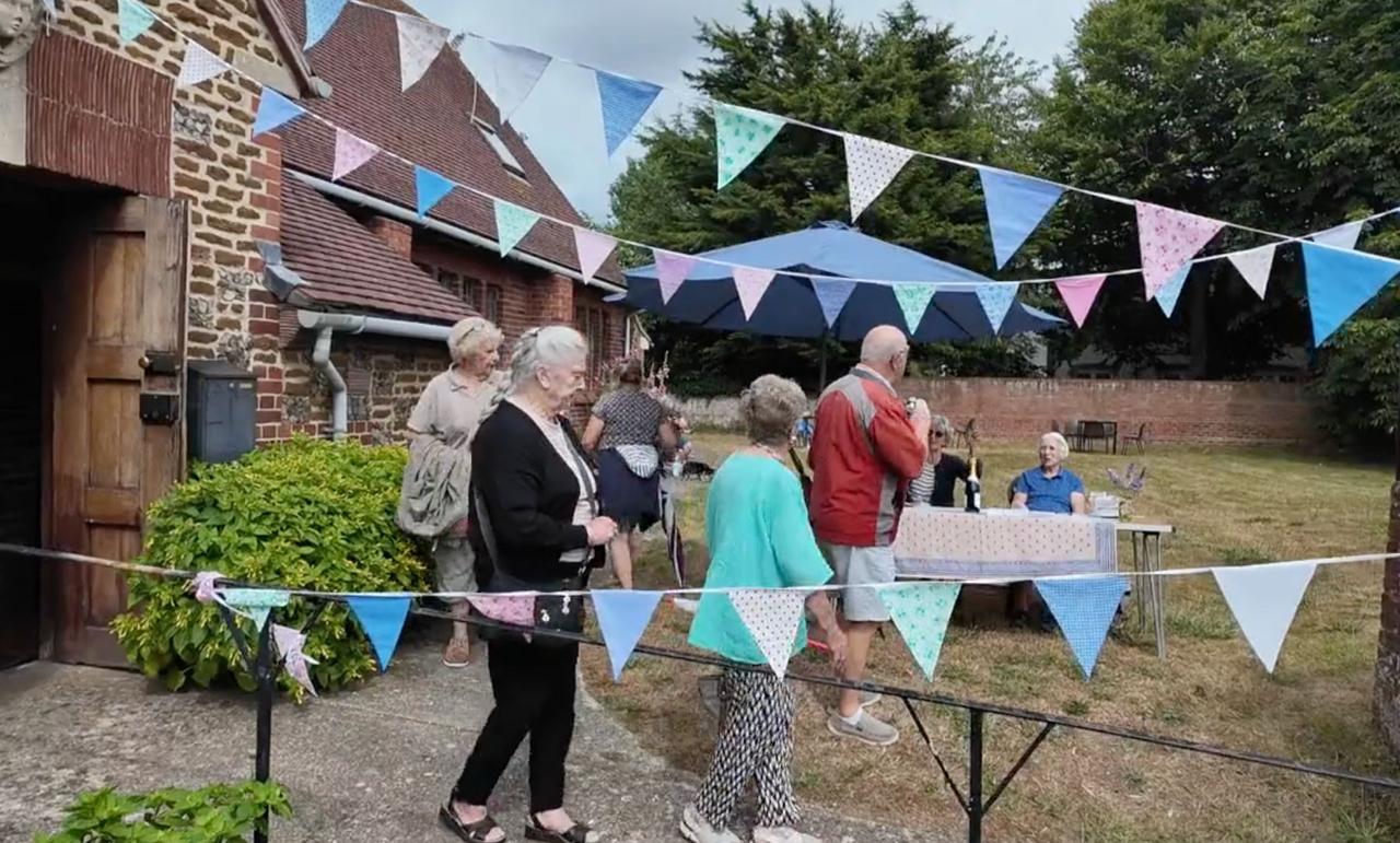 Visitors passing under bunting outside a brick and carrstone barn